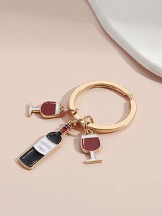 a gold keychain with a bottle of wine on it