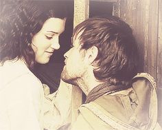 a man and woman kissing each other in front of a wooden door with an old photo frame