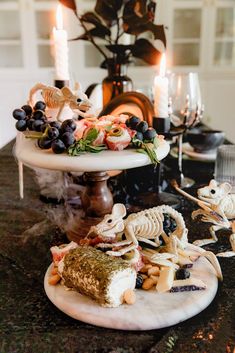 a table topped with two tiered trays filled with food and skeleton figurines