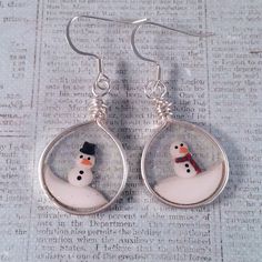 a pair of snowman earrings sitting on top of a newspaper