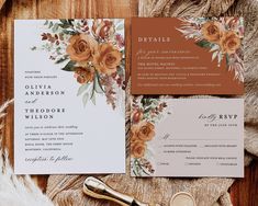 the wedding stationery is laid out on top of a wooden table with flowers and greenery