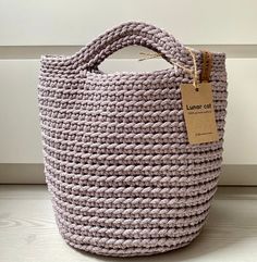 the lavender crochet bag has a tag hanging from it's front pocket