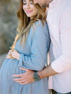 a pregnant woman and man standing next to each other with their hands on her stomach