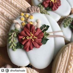 some cookies decorated with flowers and leaves on top of each other in white frosting