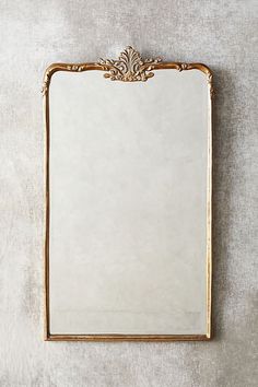 a white and gold framed mirror sitting on top of a table next to a wall