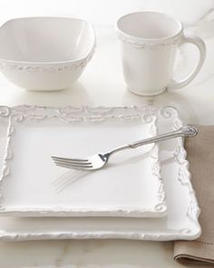 a place setting with white dishes and silverware