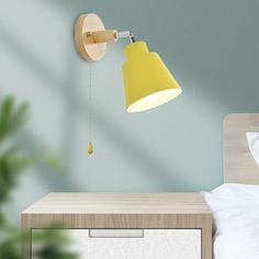 a yellow lamp is hanging on the wall next to a bed with white sheets and pillows