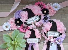 three hats with name tags on them sitting next to some flowers and ribbon around them