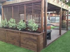 a wooden deck with planters on it next to a fence and grass covered yard