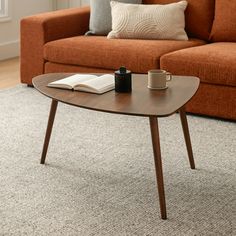 a coffee table with a book, mug and pen on it in front of a couch