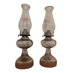 two glass candlesticks sitting side by side on top of each other with one candle in the middle