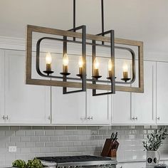 a chandelier hanging from the ceiling in a kitchen with white cabinets and counter tops