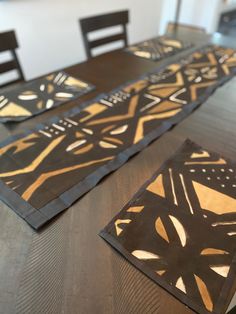 the table is set with four placemats on top of it, which are decorated with gold and black designs