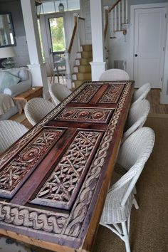 a wooden table sitting in the middle of a living room next to a stair case