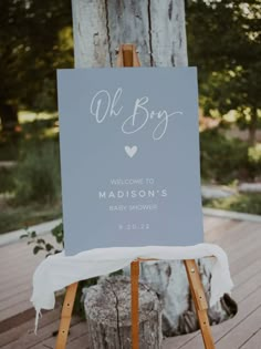 a welcome sign for a baby shower is displayed on an easel in front of a tree