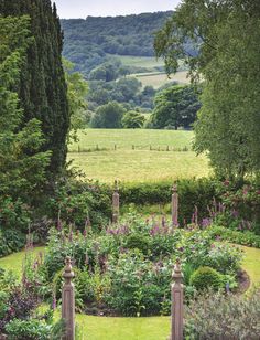 the garden is surrounded by tall trees and lush green grass, with an open field in the background