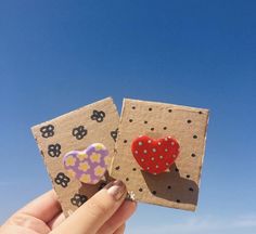 someone holding up two small magnets with hearts on them