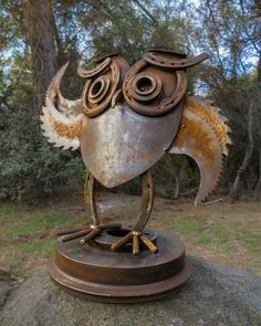 a metal bird sculpture sitting on top of a rock