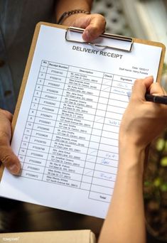 a person holding a clipboard with a receipt on it and writing down the list