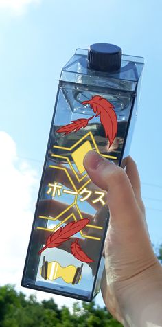 a hand holding up a water bottle with an image of two red birds on it