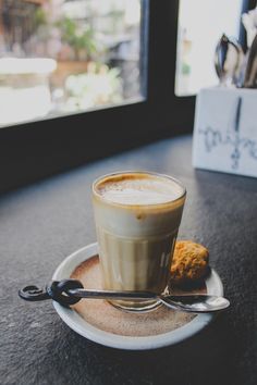 a cup of coffee on a saucer with spoons next to it sitting on a table