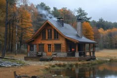 a log cabin sits on the edge of a lake in front of trees with yellow leaves