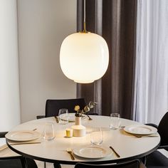 a table with plates and wine glasses on it in front of a curtained window