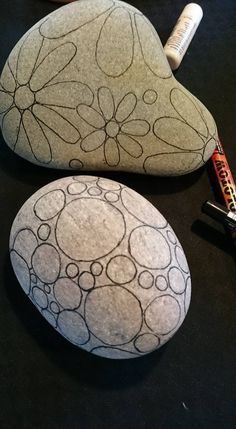 two rocks sitting on top of a table next to some pens and pencils in front of them