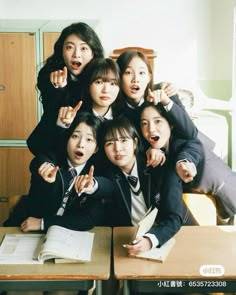 a group of young people sitting at desks posing for a photo