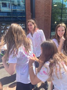 four girls in white shirts are standing together