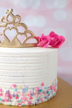 a white cake with sprinkles and a gold crown topper on it