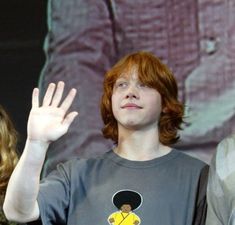 two people standing next to each other with their hands in the air and one person holding his hand up