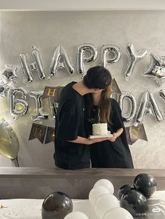 a woman standing in front of a table with a cake on it and balloons behind her