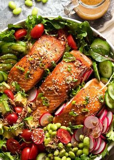 a bowl filled with salmon and vegetables next to a glass of beer