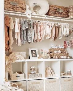 a closet filled with lots of baby clothes and baskets on top of white shelving