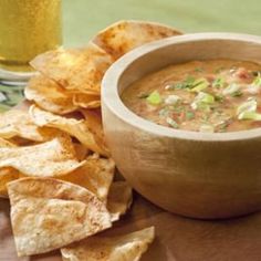 a wooden bowl filled with soup next to tortilla chips