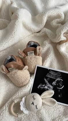 a pair of baby shoes sitting on top of a white blanket next to a stuffed animal