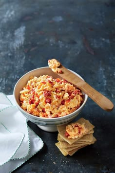 a bowl filled with food next to crackers on top of a black countertop