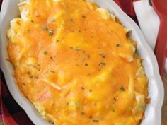 a casserole dish with cheese and herbs in it on a red and white checkered cloth