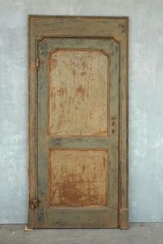 an old wooden door on the side of a building with concrete flooring and cement walls