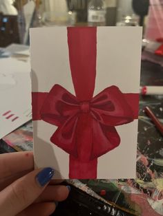 someone holding up a card with a red bow on it