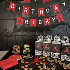 a birthday party with black and red decorations, paper bags and basketball themed items on the table