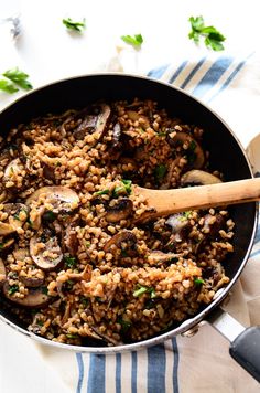 a pan filled with rice and mushrooms on top of a blue and white table cloth