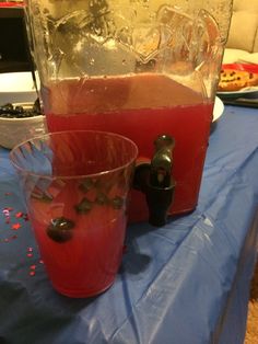 two glasses filled with liquid sitting on top of a blue tablecloth covered table next to a blender