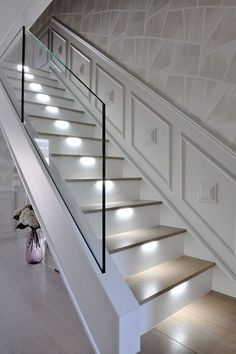 a white staircase with glass railing and lights