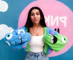 a woman standing in front of a wall with two stuffed animals on it's arms