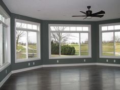 an empty room with three windows and a ceiling fan