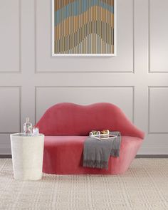 a living room with a red couch and two tables in front of a white wall