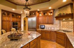 a large kitchen with wooden cabinets and marble counter tops, along with a center island