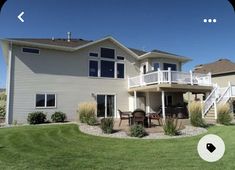 an image of a house that is in the middle of a yard with grass and bushes